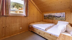 Una camera in legno con un letto, una finestra con tende e un quadro appeso al muro.