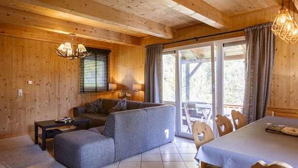 Een gezellig interieur van een chalet met een bank, eettafel en stoelen.