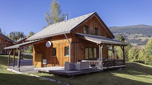 Een houten chalet met een overdekte veranda, een schotelantenne en uitzicht op het omliggende landschap.