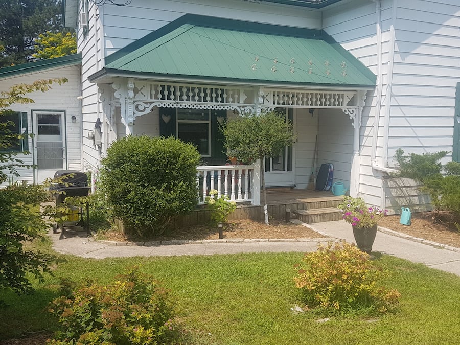 Une maison blanche avec un toit vert et une véranda.