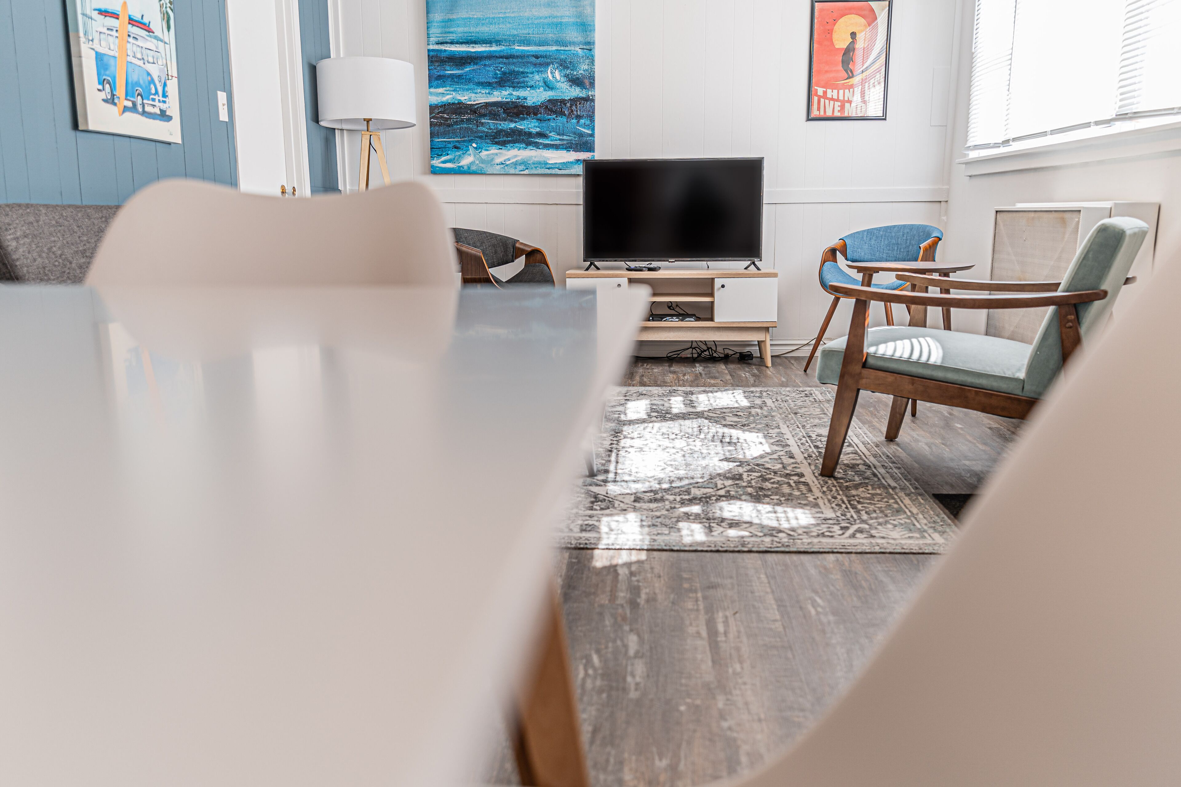 Un salon moderne avec un téléviseur à écran plat, des meubles en bois et des œuvres d’art accrochées aux murs.