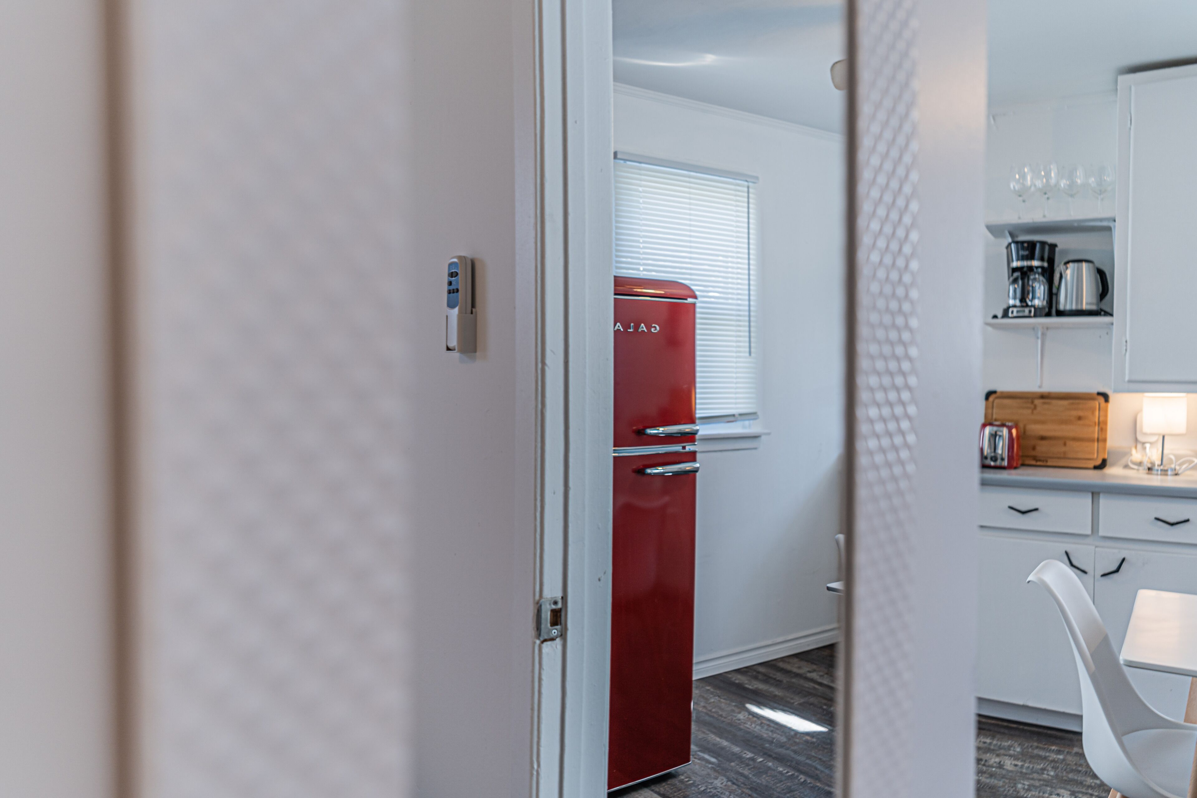 A modern kitchen with a red refrigerator, white cabinets, and a wooden countertop.
