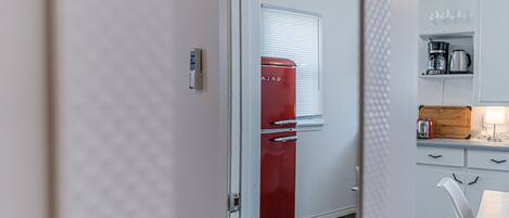 A modern kitchen with a red refrigerator, white cabinets, and a wooden countertop.