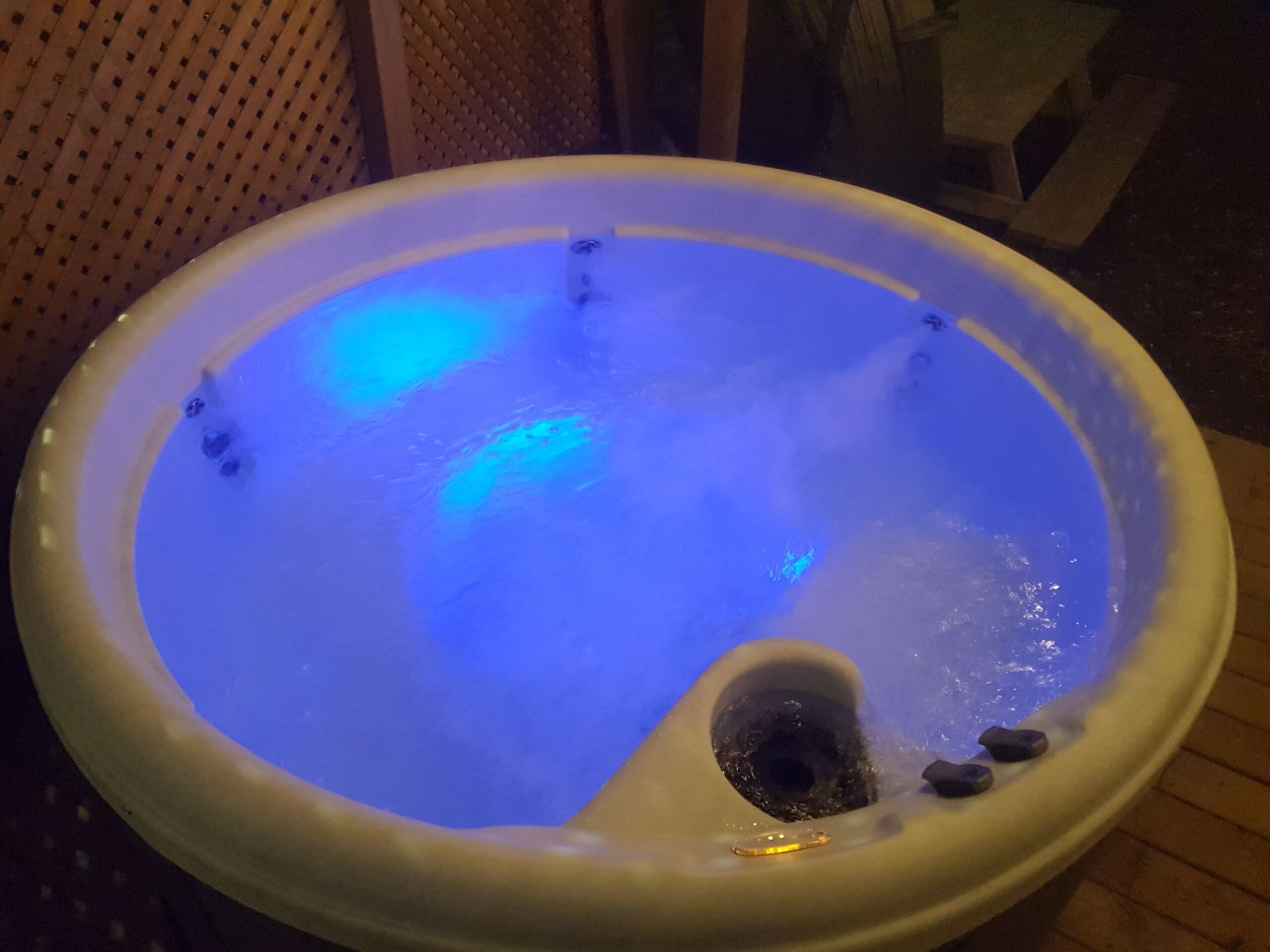 Un jacuzzi con luz azul, un desagüe y algunas piedras.