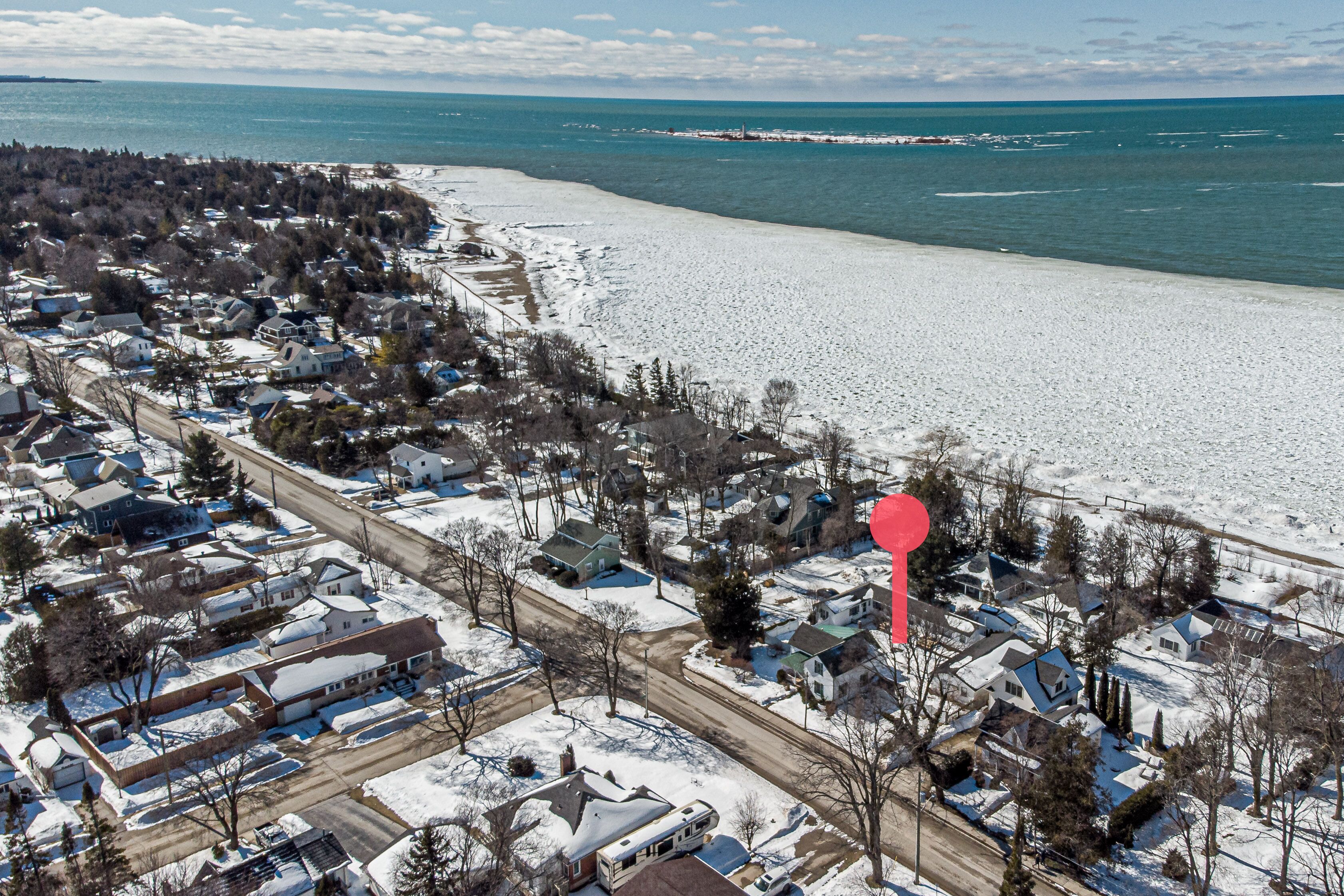 Vue aérienne d’un quartier résidentiel avec des maisons, une route et une plage.