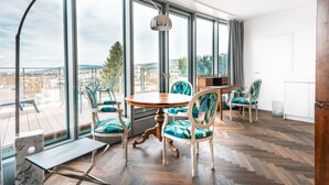 A dining area with a wooden table and chairs, large windows with a view of the city, and a herringbone floor pattern. - Hirschen Oberkirch  (Oberkirch)