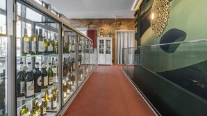 A corridor with glass display cases of wine bottles, a white cabinet, and a decorative wall piece. - Hirschen Oberkirch  (Oberkirch)