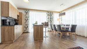 Una cocina moderna con armarios de madera, una isla central y un comedor con mesa y sillas.