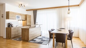 Une cuisine moderne avec des meubles en bois, un four à micro-ondes encastré et un coin repas comprenant une table et des chaises.