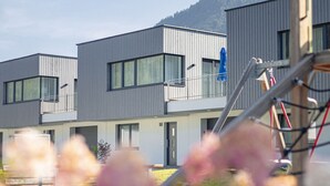 Un bâtiment moderne doté de nombreux balcons et offrant une vue dégagée sur une montagne en arrière-plan.