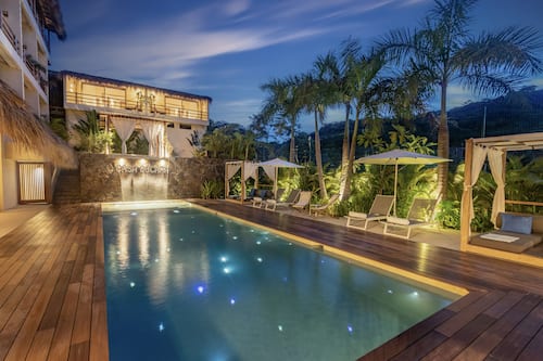 Una piscina al aire libre, sombrillas, tumbonas
