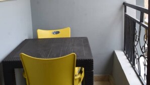Un pequeño balcón con una mesa y dos sillas amarillas.