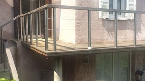 Et toetagers hus med balkon, skydedør og et lille udendørs område med planter.