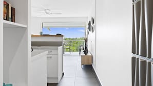 A modern kitchen with white cabinetry, a built-in oven, and a window overlooking a balcony. - Beachfront Orient Bay 1‑BR Condo • Mont Vernon • Balcony • Pool • Fast Wi‑Fi (Cul de Sac)