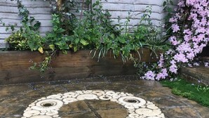 A stone patio with a circular pattern of white and beige tiles. - Apple Blossom - Chideock, Bridport (Chideock)