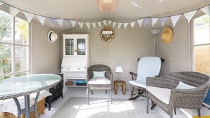A cozy, well-lit room with a glass table, wicker furniture, a white cabinet, and a decorative wreath. - Apple Blossom - Chideock, Bridport (Chideock)