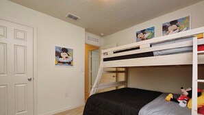 A bunk bed room with Mickey Mouse posters, a door, and a carpeted floor.