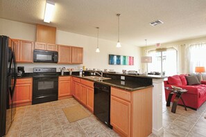 A modern kitchen with wooden cabinets, a built-in microwave, a dishwasher, and a granite countertop.