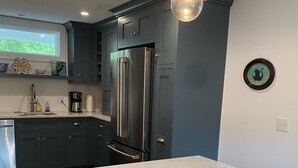 Une cuisine moderne avec des meubles de couleur sombre, un réfrigérateur en acier inoxydable et un plan de travail en marbre.