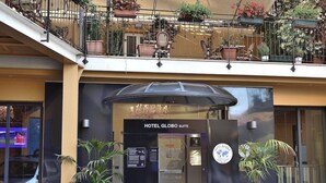 Der Eingang zum Hotel Globo Suite mit modernem Design, mit einer Glaskuppel und Topfpflanzen.