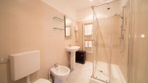Ein modernes Badezimmer mit Toilette, Bidet, Waschbecken und einer Duschkabine.