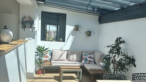 A modern interior with a wooden floor, a sofa, a table, and a dining area.