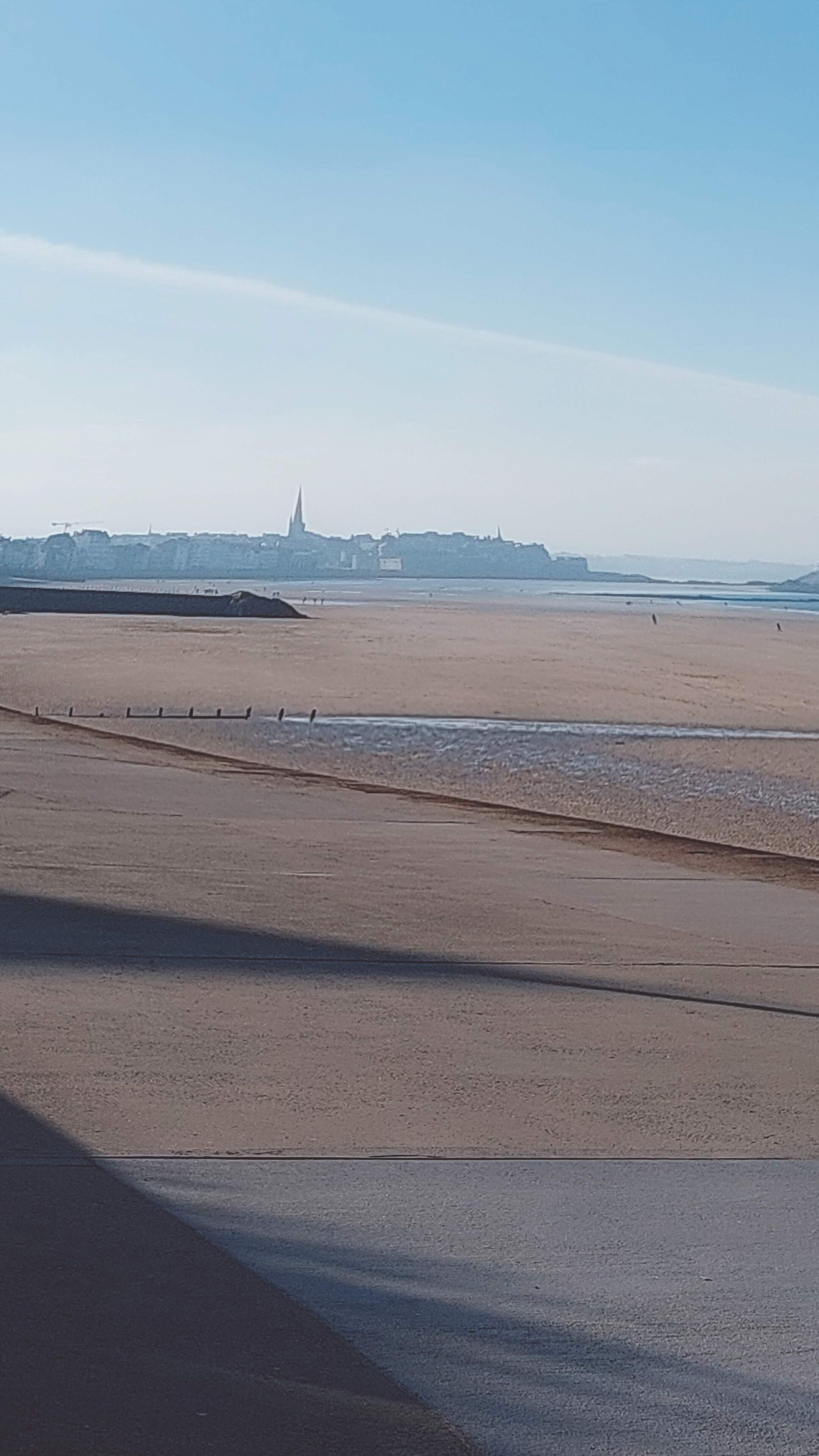 A wide sandy beach with a clear sky.