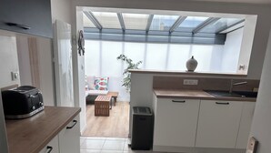 A modern kitchen with a toaster, a sink, a window with a view, and a small seating area.