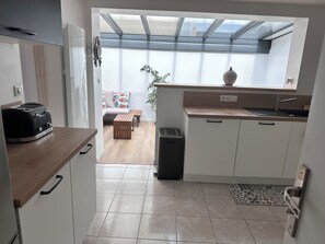 A modern kitchen with a toaster, a sink, and a window overlooking a living area. - CHARMING RENOVATED HOUSE BY THE SEA DIRECT ACCESS TO THE MONT SAINT-MICHEL BAY (Cherrueix)