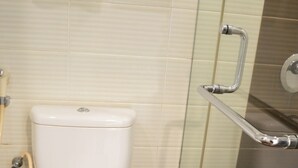 A bathroom with a white toilet, a glass shower enclosure, and a tiled floor.