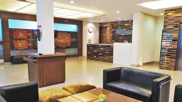 A modern hotel lobby with leather seating, a reception desk, and a decorative wall.