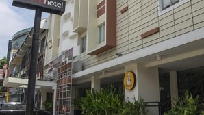 A hotel with a modern design, featuring a prominent 'd'prima hotel' sign, a logo on the building, and a parking area with bollards.