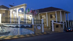 A building with a large entrance, columns, and flags. - Sonia Hotel (Accra)