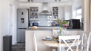 Une cuisine moderne avec des meubles blancs, un four encastré et une machine à café.