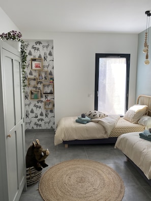 A bedroom with a bed, a small rug, a stuffed animal, and a wall with animal-themed wallpaper. - Sun Pines (Hourtin)