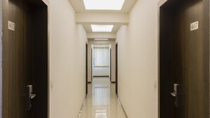 A corridor with doors labeled 402 and 407, leading to a room with a window and a door at the end. - Fabhotel Arya Regency Hinjewadi (Paud)