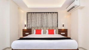 A modern bedroom with a large bed, wooden headboard, and a ceiling light fixture. - Fabhotel Arya Regency Hinjewadi (Paud)