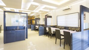 A modern dining area with booths and tables, recessed ceiling lights, and an air conditioning unit. - Fabhotel Arya Regency Hinjewadi (Paud)