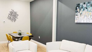 Un saló modern amb un sofà blanc, una butaca a joc, una taula de centre i una zona menjador amb taula i cadires.