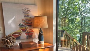 A wooden dresser with drawers, a lamp, and a painting of boats.