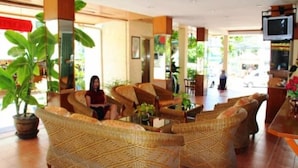 Un hall con mobiliario de mimbre, un televisor y plantas en macetas.