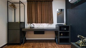 Una habitación pequeña con escritorio, una estantería, radiador y ventana con cortinas.