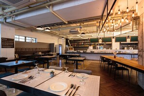 A restaurant interior with high tables, chairs, and a bar area.