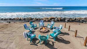 A beach setting with a fire pit surrounded by chairs, overlooking the ocean. - Guest Favorite! Fire Ring on Sand Walk to Village (Oceanside)