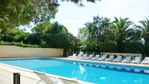 A swimming pool with white lounge chairs and a clear blue pool. - Villa Tout Confort 400 m de la Plage (Porto-Vecchio)