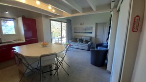A modern kitchen with a dining area, a sofa, and a trash bin. - Villa Tout Confort 400 m de la Plage (Porto-Vecchio)