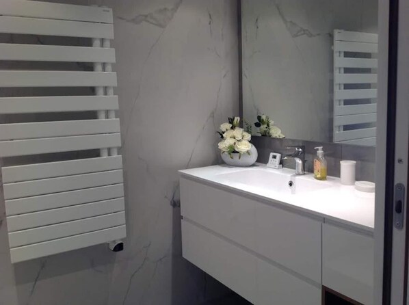 A modern bathroom with a white vanity, a large mirror, and a white towel rack. - Villa Tout Confort 400 m de la Plage (Porto-Vecchio)