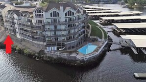 Um edifício de vários andares com piscina, situado perto de um corpo d'água com cais.