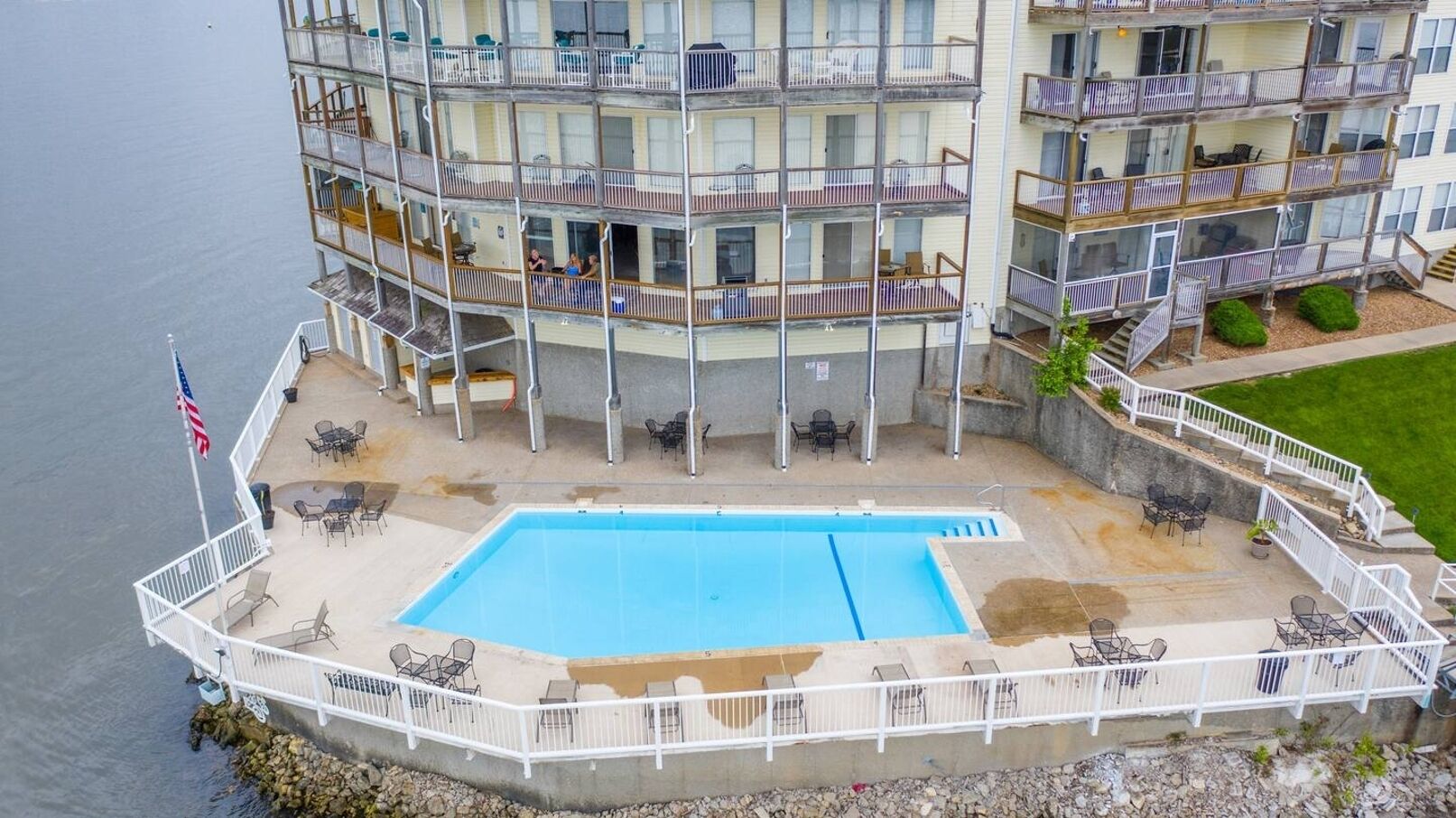 A multi-story hotel with a swimming pool, outdoor seating, and balconies.