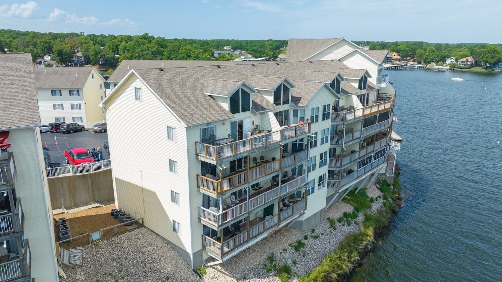 A multi-story waterfront hotel with balconies, a parking area, and a view of the river.